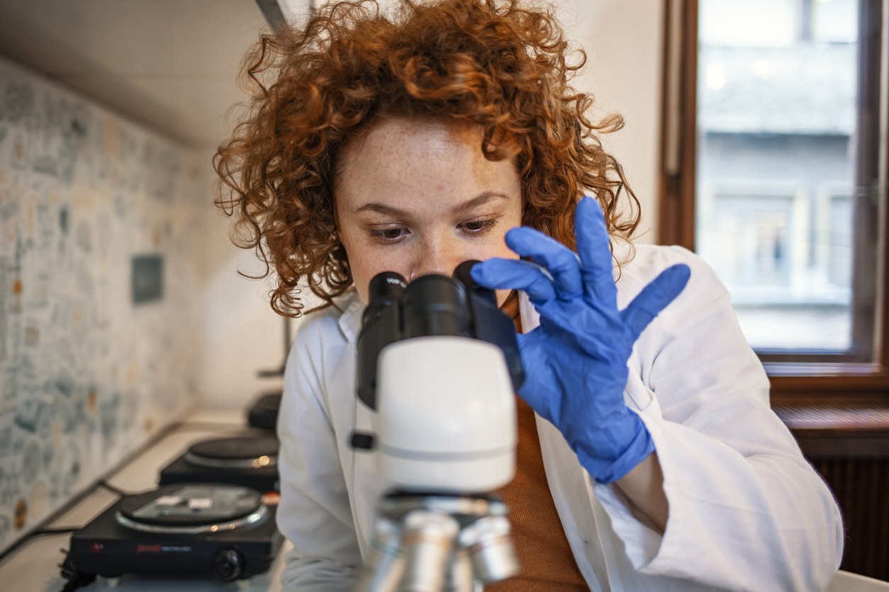 Young Scientist Working With The Microscope Scientist researcher using microscope in laboratory. Medical healthcare technology and pharmaceutical research and development concept. Young Scientist Working With The Microscope